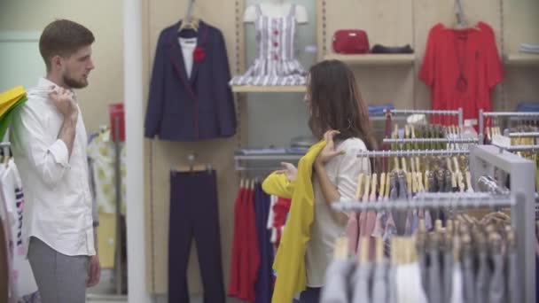 Молода Щаслива Пара Купує Разом Одяг Модному Магазині Посміхаючись Задоволені — стокове відео