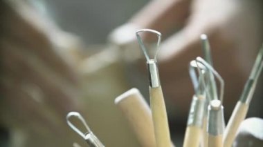 Potter 'ın elinin yakın çekimi Potter' ın tekerleğinde bir sürahi kil yontuyor.