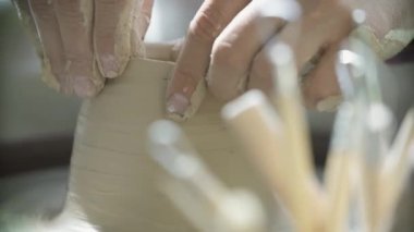 Potter 'ın elinin yakın çekimi Potter' ın tekerleğinde bir sürahi kil yontuyor.