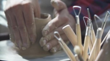 Potter 'ın elinin yakın çekimi Potter' ın tekerleğinde bir sürahi kil yontuyor.