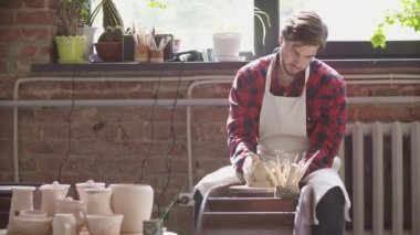 Kendi atölyesinde yeni kil öğe üzerinde çalışan iş giyim genç başarılı çömlekçi