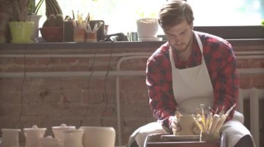 Kendi atölyesinde yeni kil öğe üzerinde çalışan iş giyim genç başarılı çömlekçi