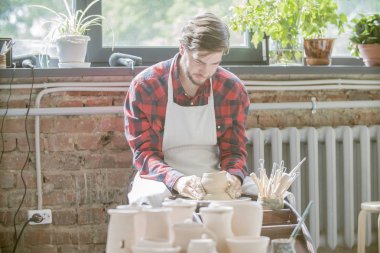 Kendi atölyesinde yeni kil öğe üzerinde çalışan iş giyim genç başarılı çömlekçi