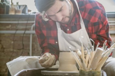 Kendi atölyesinde yeni kil öğe üzerinde çalışan iş giyim genç başarılı çömlekçi