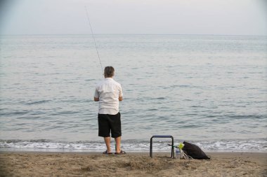 Sahilde elinde sörf tahtası olan bir adam.