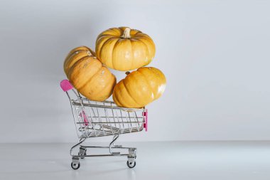 Bayram indirimleri ve sonbahar satışlarının sembolü olarak süpermarketten sepetli Cadılar Bayramı balkabakları.