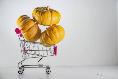 Bayram indirimleri ve sonbahar satışlarının sembolü olarak süpermarketten sepetli Cadılar Bayramı balkabakları.