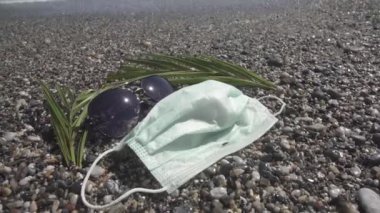 Plajda tıbbi maske var. Koronavirüs salgını sırasında dinlenin.