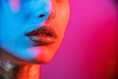 Model metalik gümüş dudaklar ve neon mavisi ve mor renkli yüzlü kadın, stüdyoda poz veriyor, güzel kız, parıldayan makyaj, renkli.. 