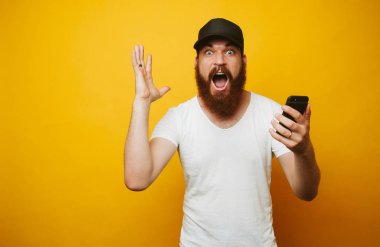 Telefon sarı arka plan üzerinde tutarak şok sakallı adam.