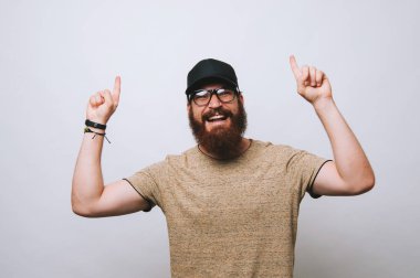 Genç adam kameraya gülümseyen iki eliyle işaret eden oktan yukarı sakallı.