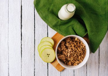 Sağlıklı kahvaltı konsepti ile yulaf gevreği ve rustik arka plan üzerinde taze yeşil elma. Granola yapılan yemekleri müsli. 