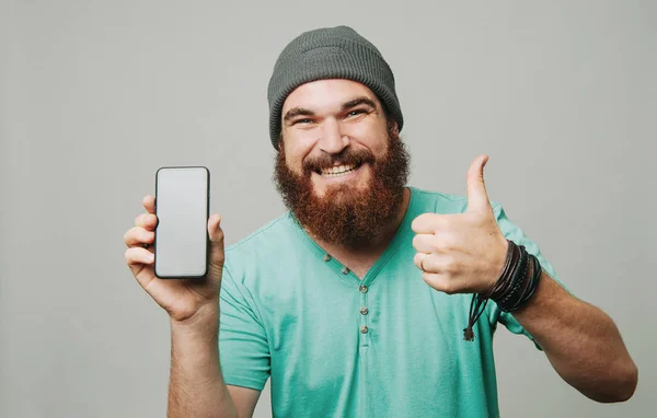 Lycklig Man Med Skägg Visar Smartphone Och Tummen Upp Gest — Stockfoto