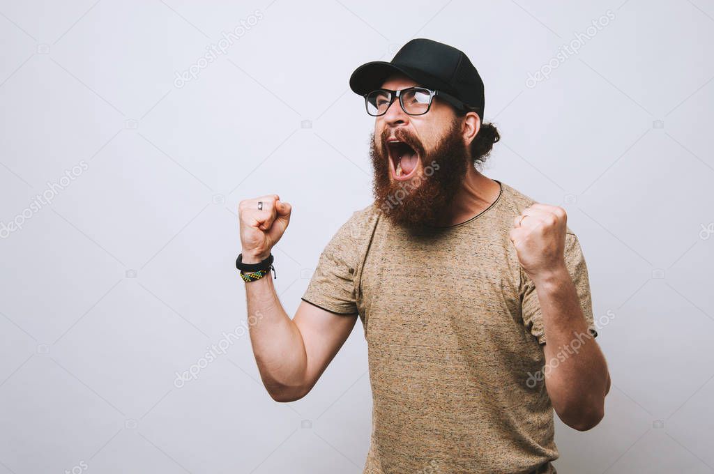 Bearded man in black hat screaming over white background