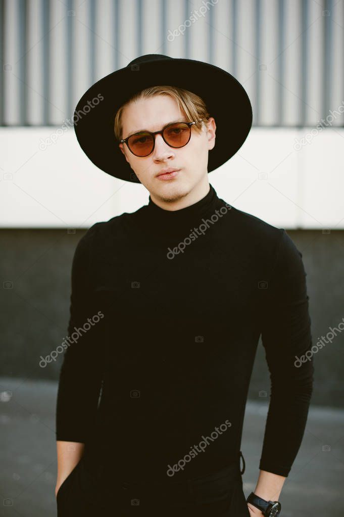 Portrait of handsome man wearing black hat and sunglasses outdoor and looking at the camera