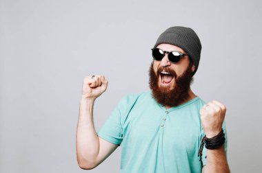 mutlu hayran sakallı hippi erkek güneş gözlüğü takıyor izole üzerinde gri arka plan exults