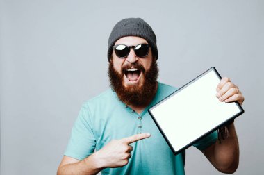 Kameraya bakarak ve beyaz tablet ekranına işaret gözlük, adam heyecanlı Genç sakallı.