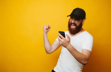 Sakallı adam başarısını kutlamak mutlu ve telefon bakarak