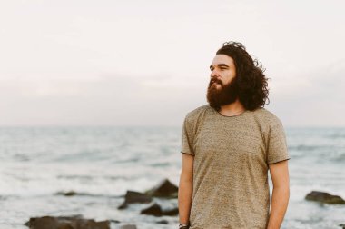 Mutlu adam uzun kıvırcık saç denize yakın açık rahatlatıcı ile sakallı