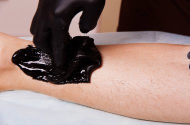 Yapıştır saçlı bacak el ile siyah eldiven koymak sugaring siyah.