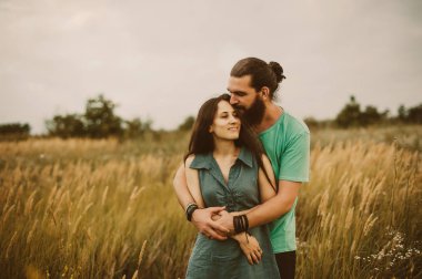 INLOVE kucaklayan ve gülümseyen birbirlerine sarılma bir alan üzerinde bir çift gördüm. Uzun saçlı kadın ve erkek genç sakallı.