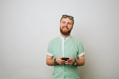 Beyaz arka plan üzerinde telefon kullanan yenilikçi adam genç gülümseyen sakallı