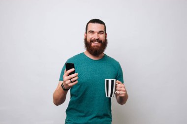 Bir telefon tutarak ve çay içme mutlu sakallı adam portresi