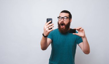 Kredi kartı ve smartphone, hayretle açılan ağzından ile beyaz arka plan üzerinde ayakta tutan şok ve dehşet içinde Avrupa gencin Studio vurdu. Hesabımdan para çalınması