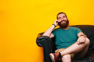 Kanepeye siting ve telefonda konuşurken sakallı mutlu adam