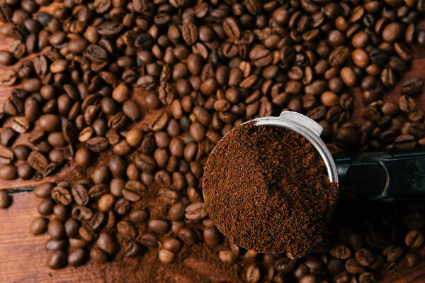 Some ground coffee on beans of coffee background on a wooden table. Close up, top view.