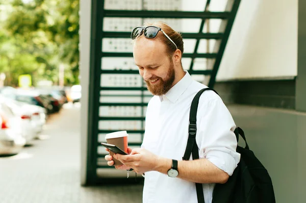 Young hipster man walking on the street and using his smartphone — Stock Photo, Image