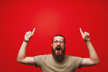 Gözlük takan ve boşaltmak kırmızı arka plan üzerinde yukarı dönük hayret sakallı adam