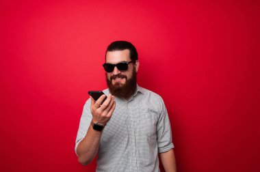 Sakallı adam kırmızı arka plan üzerinde telefon kullanma