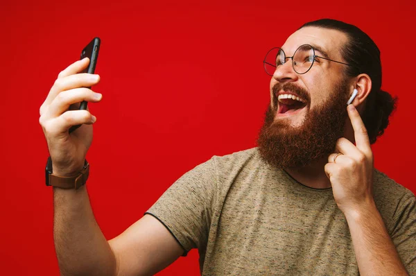Счастливый Человек Бородой Слушает Музыку Воздушных Стручках Красном Фоне — стоковое фото