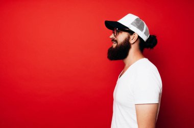 Yan bakış beyaz t-shirt ve giyen mutlu sakallı adamın beyaz kap