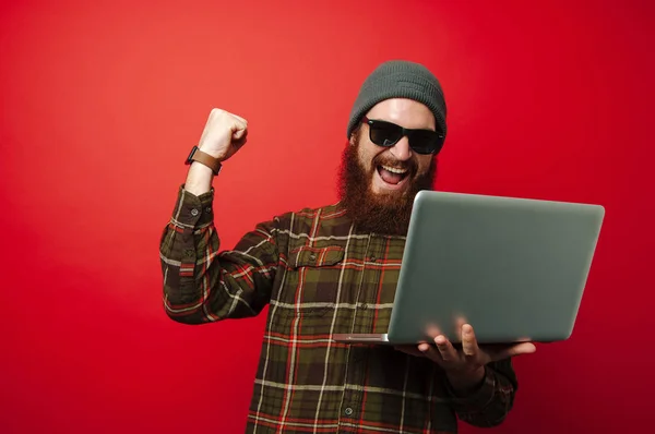 Glücklicher Junger Bärtiger Mann Blickt Auf Laptop Und Feiert Erfolg — Stockfoto