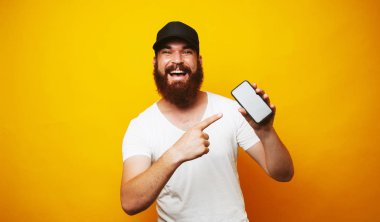 Smartphone vasıl sarı arka plan üzerinde işaret mutlu sakallı hippi adam