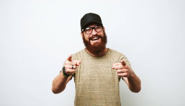 Neşeli sakallı hippi adam kameraya beyaz arka plan üzerinde işaret