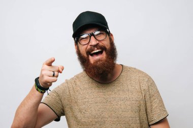 Sakallı adam kameraya beyaz arka plan üzerinde işaret gülümseyen