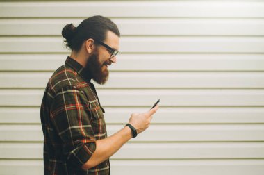 Telefon kullanan genç neşeli sakallı hippi adam 