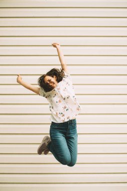 Mutlu genç kadın duvar arka plan üzerinde atlama