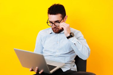 Sarı arka plan üzerinde dizüstü bilgisayar kullanan adam