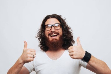 Başparmak gösterilmesini ve beyaz arka plan üzerinde gülümseyen neşeli yakışıklı sakallı adam