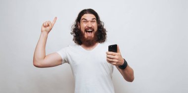 Yukarı dönük ve telefon tutarak heyecanlı berded adam 