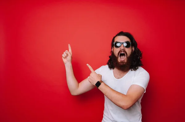 Excited man with beard pointing away at copyspace