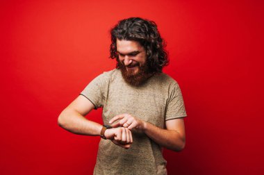 Neşeli sakallı adam uzun saçlı smartwatch kullanarak
