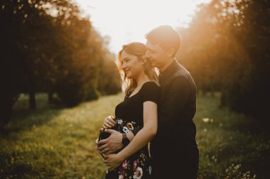 Gün batımında park, meternity kavramı kucaklayan genç çift