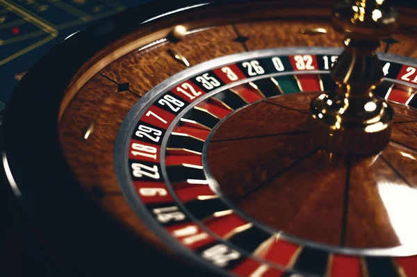 Roulette table in casino, with many games and slots, roulette wheel in the foreground. Golden and luxury light, casino interior. Gambling is the wagering of money or playing games of chance for money