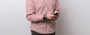 Casual adam smartphone beyaz duvardan tutan zincirler elleriyle