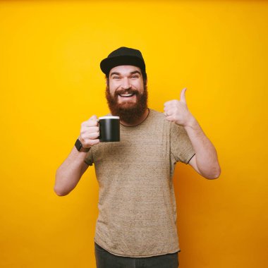 Sarı arka plan üzerinde gösterilen ve fincan sade kahve tutarak mutlu sakallı adam yaşasın